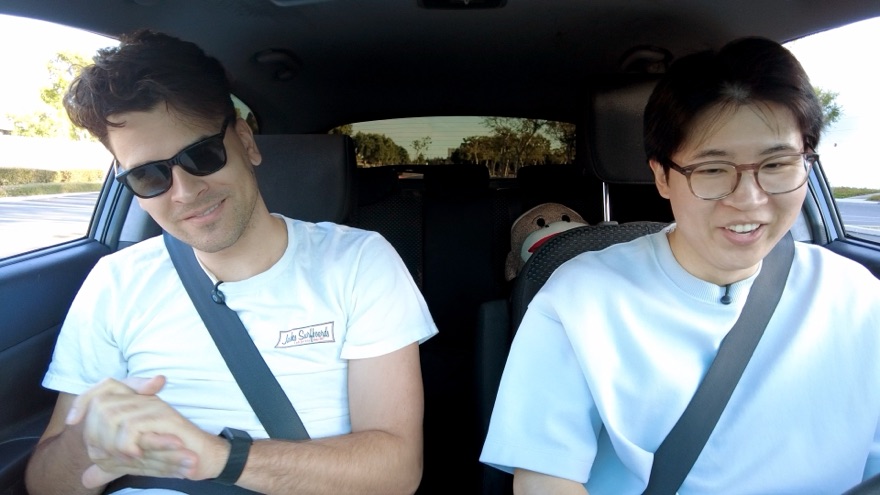 A student in sunglasses and Yuji smiling together in the car